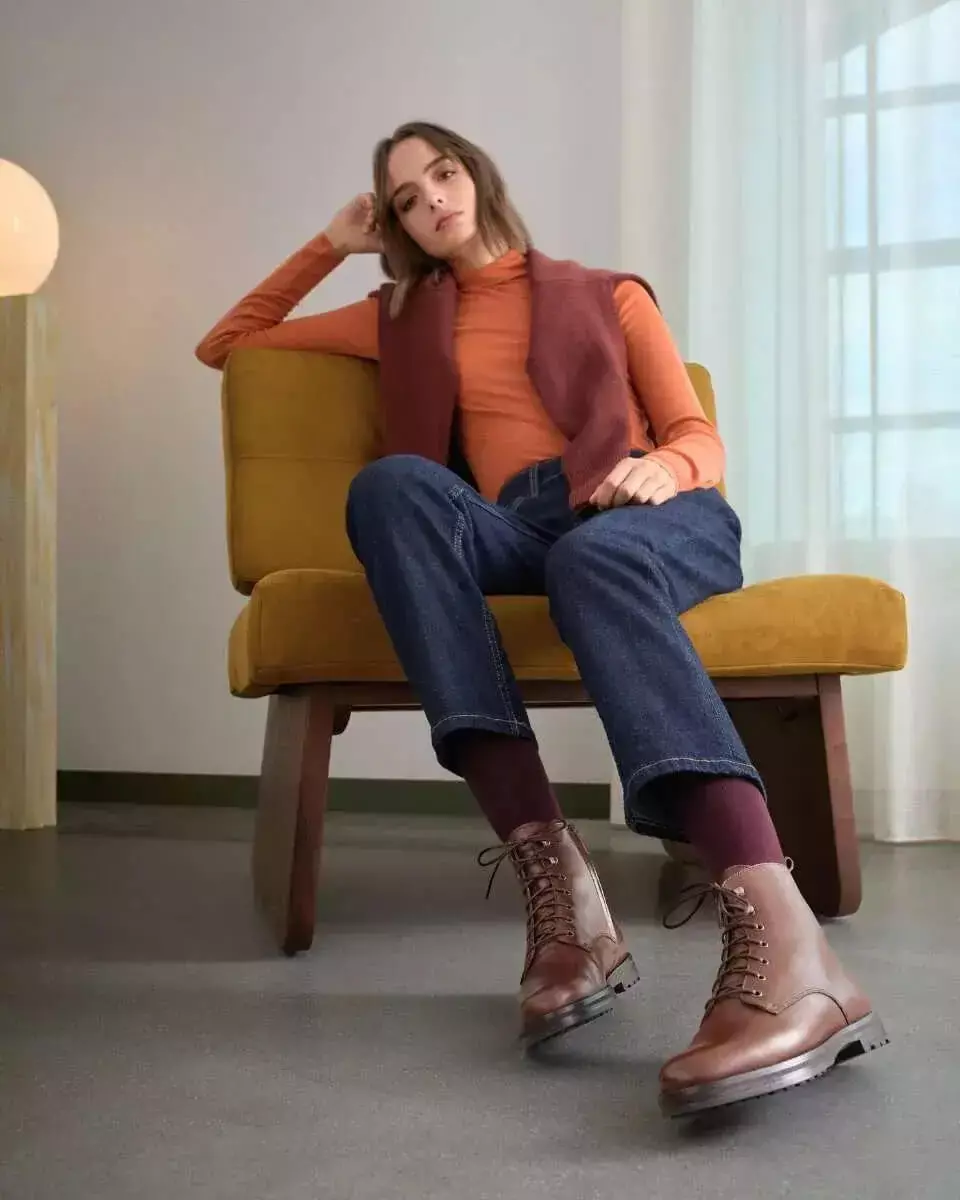 Femme assise dans un fauteuil jaune, en bottines à lacets marron